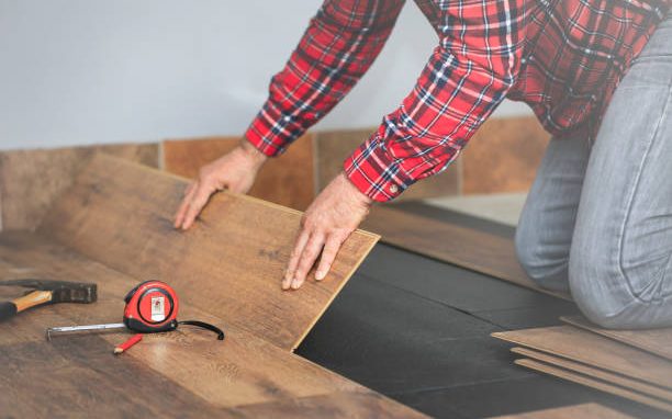 Installer laying new hardwood flooring in a bright room